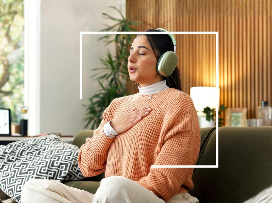 Person med hovedtelefoner mediterer i en sofa.